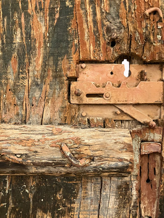 Close up of grungy, old, brown, wooden door with lock and nails. High quality photo