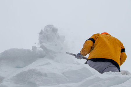 Man clean a roof from snow by shovel. Spring snow removing after blizzard. shoveling fresh wet snow off roof.の写真素材