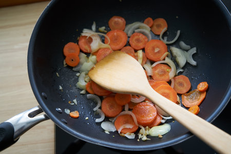 Beautiful woman posing - portrait of carrots, spatula, onions and garlicの写真素材