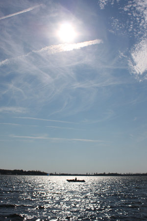 Cloudy trails on a blue sky over a lakeの写真素材