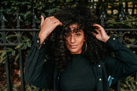 Portrait Charming Young African Woman with Curly Hair, Street Style, Posing Outdoorsの写真素材