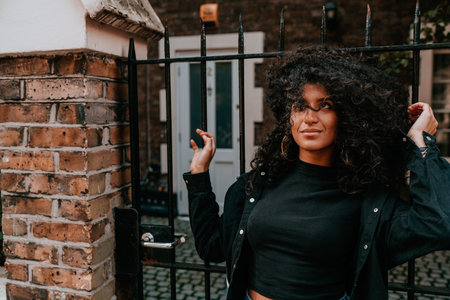 Portrait Charming Young African Woman with Curly Hair, Street Style, Posing Outdoorsの写真素材