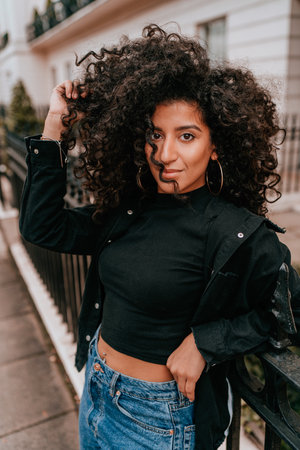 Portrait Charming Young African Woman with Curly Hair, Street Style, Posing Outdoorsの写真素材