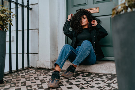 Portrait Charming Young African Woman with Curly Hair, Street Style, Posing Outdoorsの写真素材