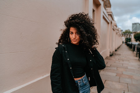 Portrait Charming Young African Woman with Curly Hair, Street Style, Posing Outdoorsの写真素材