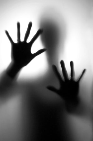 Person in fear - Silhouette of a woman, defending her self with here hands.の写真素材