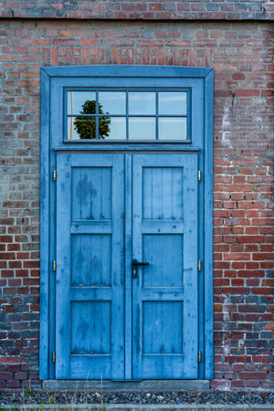 Old blue rusted door in industrial area against light colored brick wallの写真素材