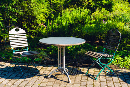 Wooden partition, wooden tiles, two white garden chairs and a round table on the terrace of a residential building.の写真素材