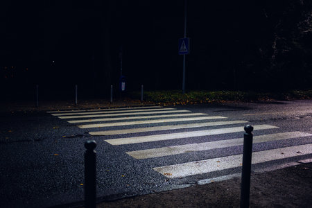 City street with blurred cars and wet asphalt closeup of a white pedestrian cross overの写真素材