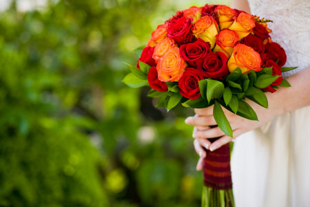 Bride holding wedding bouquet of Roses and Ruscus flowersの写真素材