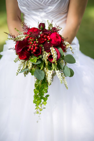 Wedding bouquet of flowers including Red hypericum, Roses, Lilies of the valley, mini Roses, Seeded Eucalyptus, Astilbe, Scabiosa, Pieris, and ivyの写真素材