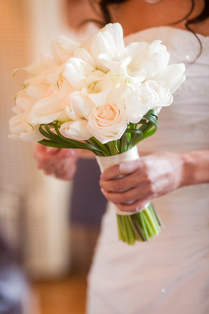 Bride holding beautiful bouquet of white flowers consisting of white tulips, white calla lilies, ivory rosesの写真素材