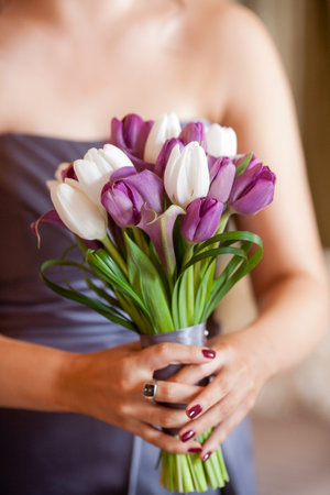Bridesmaid holding a bouquet of flowers consisting of Lavender calla Lilies, purple tulips, white tulipsの写真素材