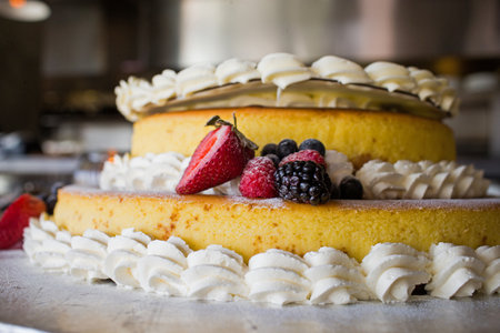 Sliced strawberries and blueberries placed on top of a delicious cakeの写真素材