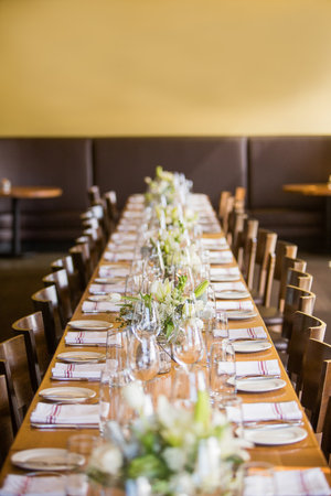 Long table in a restaurant set for an event such as a wedding reception or banquet
