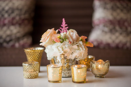 Small arrangement of flowers on a table surrounded by candlesの写真素材