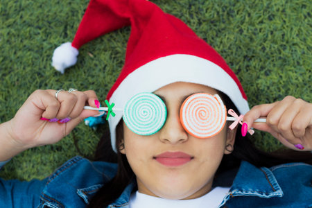 Girl with Christmas details, posing with Christmas hat, stars, candiesの写真素材