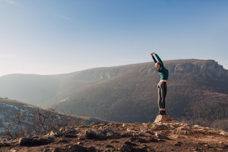 Young fit woman exercising on a mountain topの写真素材