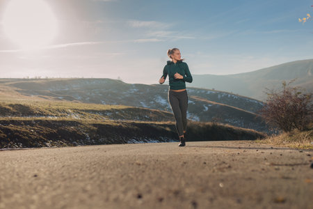 Young fit woman running outside in a hoodieの写真素材