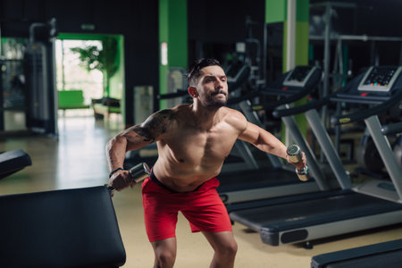 Strong man in the gym doing shoulder exercises with dumbbellの写真素材