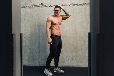 Young strong man in glasses near a concrete wallの写真素材