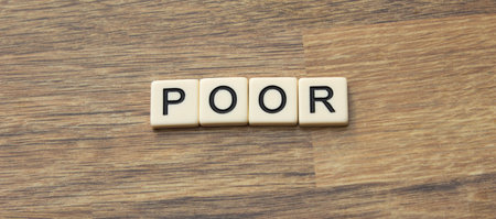 The word poor written in tiles on a wooden surfaceの写真素材