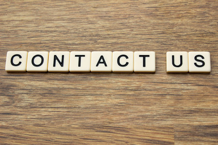 The word contact us written in tiles on a wooden surfaceの写真素材