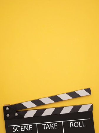 Film clapperboard on yellow background. Entertainment concept.の写真素材
