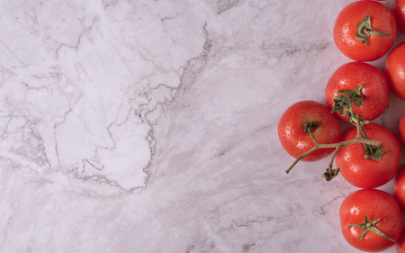 Top view of tomatoes with water droplets on a marble table