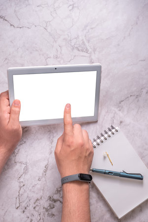 Hands of an unknown person using a tablet on a marble background.の写真素材