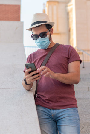 Tourist looking at his cell phone while wearing a face mask.の写真素材