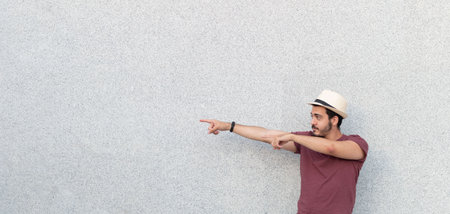 Young man wearing a hat while pointing to the side of a copy space area.の写真素材