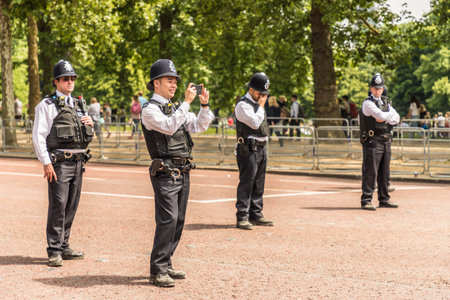 London. June 9 2018. A view of a police officer taking pictures for tourists during the Queens birthday celebrations of Trooping the Colourのeditorial素材