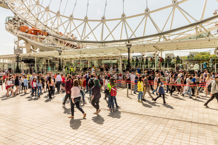London. June 2018. A view of tourists walking next to the London Eye along the south bank in Londonのeditorial素材