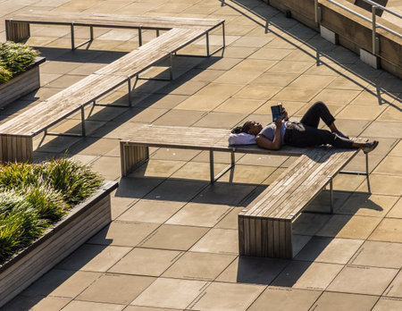 London. June 2018. A view of a female relaxing on modern benches along the south bank in Londonのeditorial素材