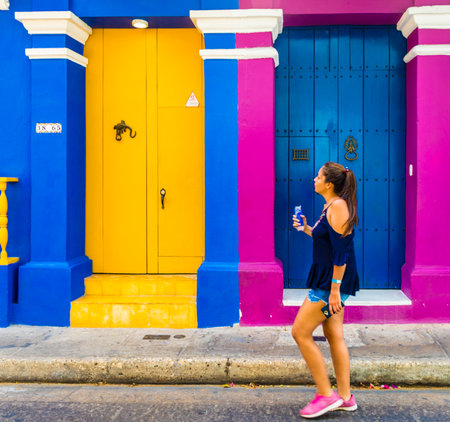 Cartagena, Colombia. April 2018. A view of a girl walking past a bcolorful colonial building in Cartagena, Colombia.のeditorial素材