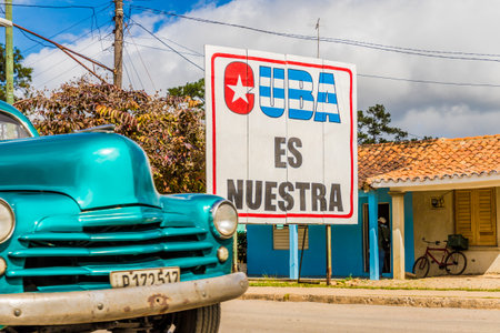 Vinales Valley, Pinar del Rio, Cuba. January 2018. A view of a vintage American car passing a local sign saying Cuba is ours in Vinales Valley in Cuba.のeditorial素材