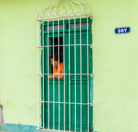 Trinidad Cuba. January 2018. A view of a local lady looking through a window in Trinidad, Cubaのeditorial素材
