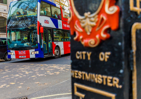 London. November 2018. A view of a traditional london bus passing a city of london lampost in Londonのeditorial素材