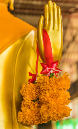 Marigold flowers on a golden buddha at the Big Buddha statue in Phucket Thailandの写真素材