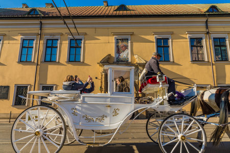 Krakow Poland. April 2019. A view of a horse drawn carriage passing Archbishops palace in the medieval old town in Krakow Polandのeditorial素材