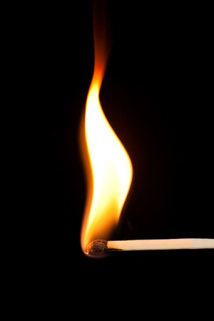 Match bursting into flame against a black background