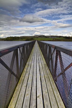 Long footbridge stretching into the distance across a wide lakeの写真素材