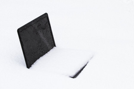 A frozen laptop computer half buried in a snow driftの写真素材