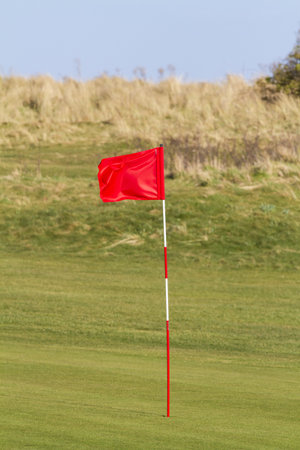 Red golf flag on a seaside links course in the UKの写真素材