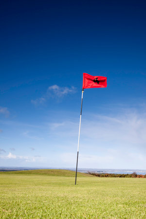 Close up of a golf flag and green on a bright sunny dayの写真素材