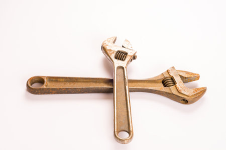 Two old rusty adjustable wrench crossed over each other on plain backgroundの写真素材