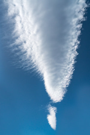 Long arrow shaped cloud against a bright blue skyの写真素材