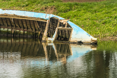 Close up of Half submerged boat wreck on the banks of a riverの写真素材