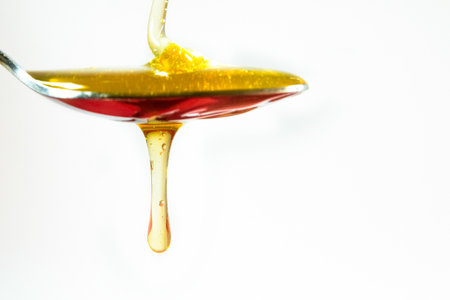 honey pouring in a spoon on white backgroundの写真素材